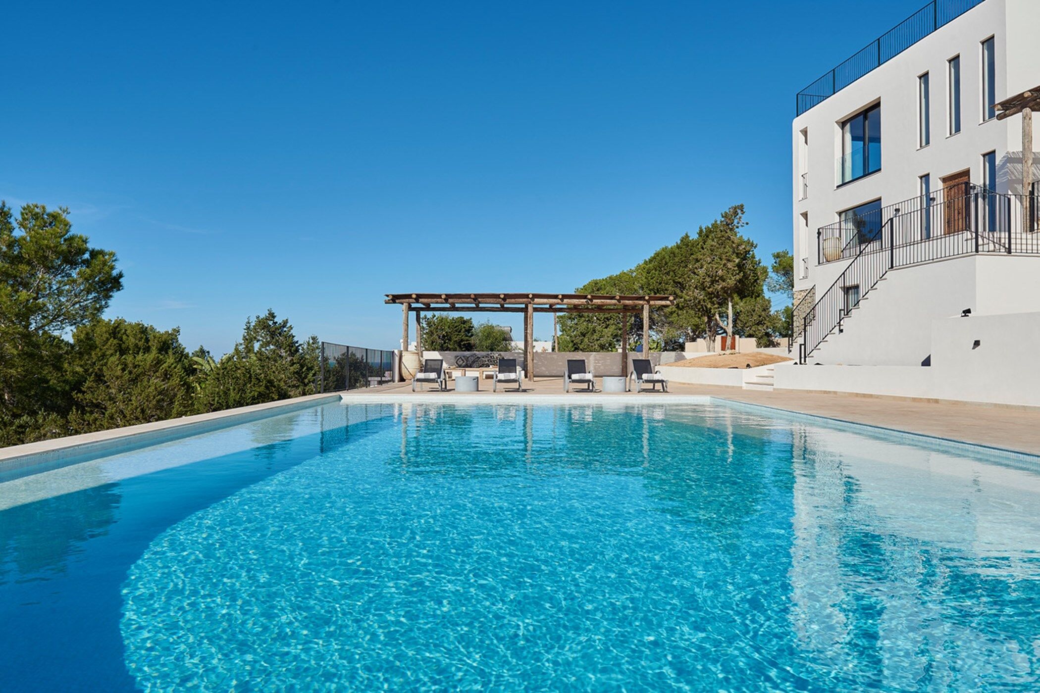 The large swimming pool Los Pinos with a view towards the shaded pergola and sun loungers