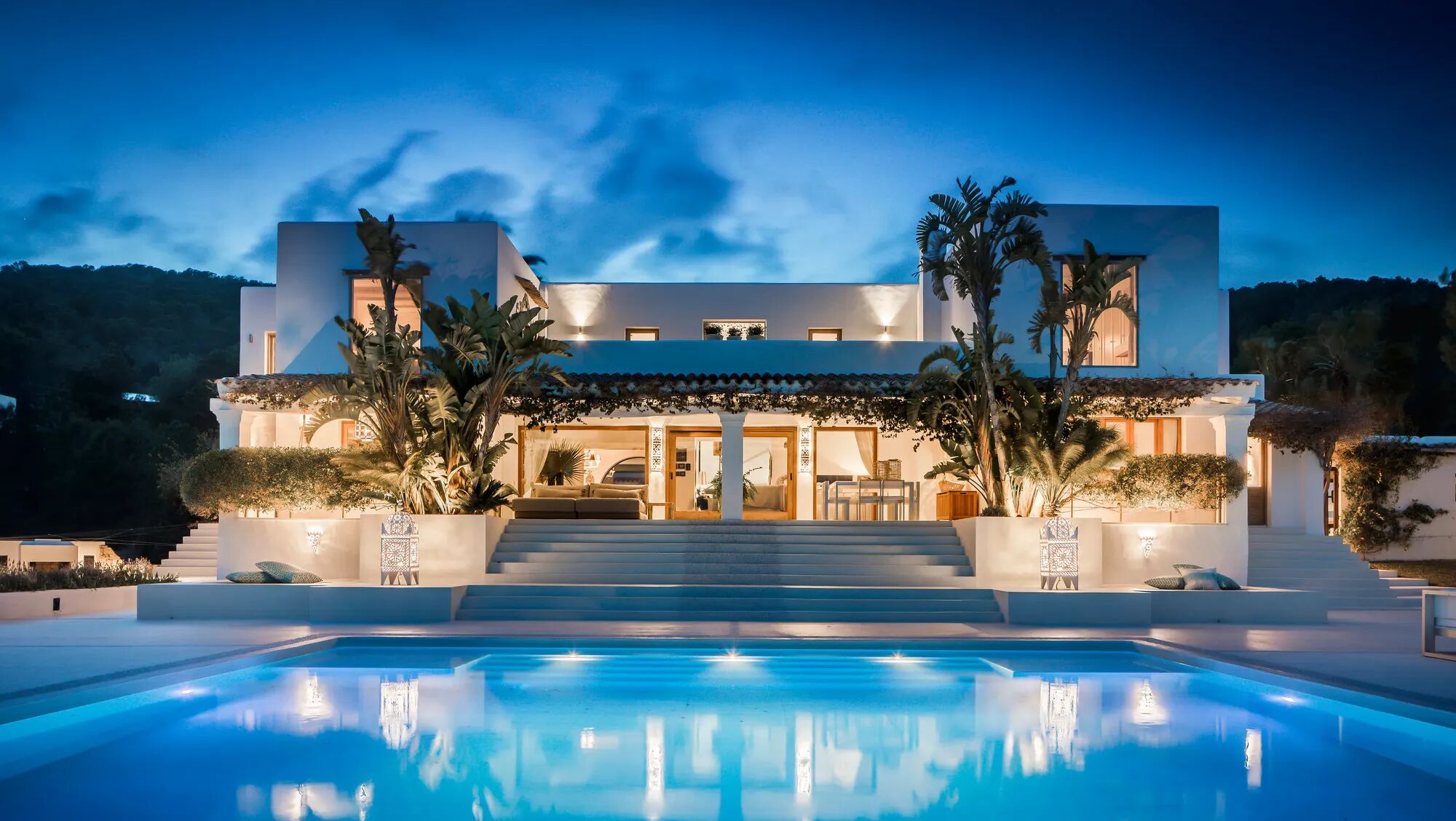 Luxury rental Villa Lamp in Ibiza with modern architecture, featuring a large pool surrounded by greenery and a spacious terrace