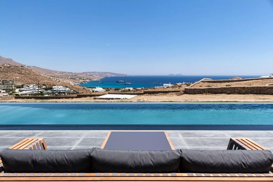 Incredible view from the seating area at vacation rental Villa Manifica of the infinity pool that overlooks the hills of Mykonos and the sea