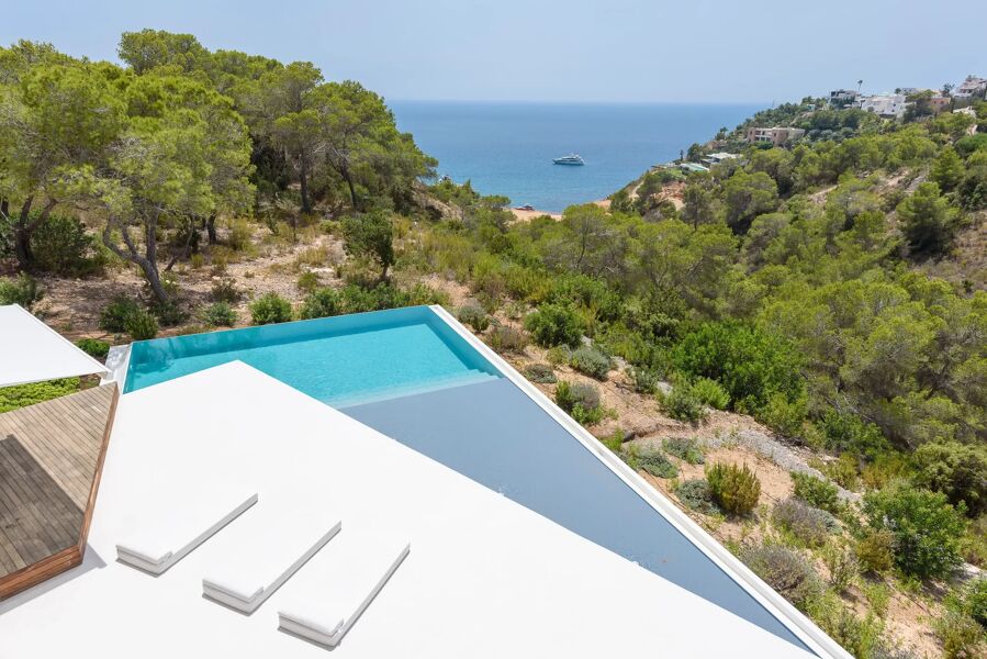 View of the infinity pool and sunloungers of Villa Viola looking down the Ibizan hills into the Mediterranean Sea