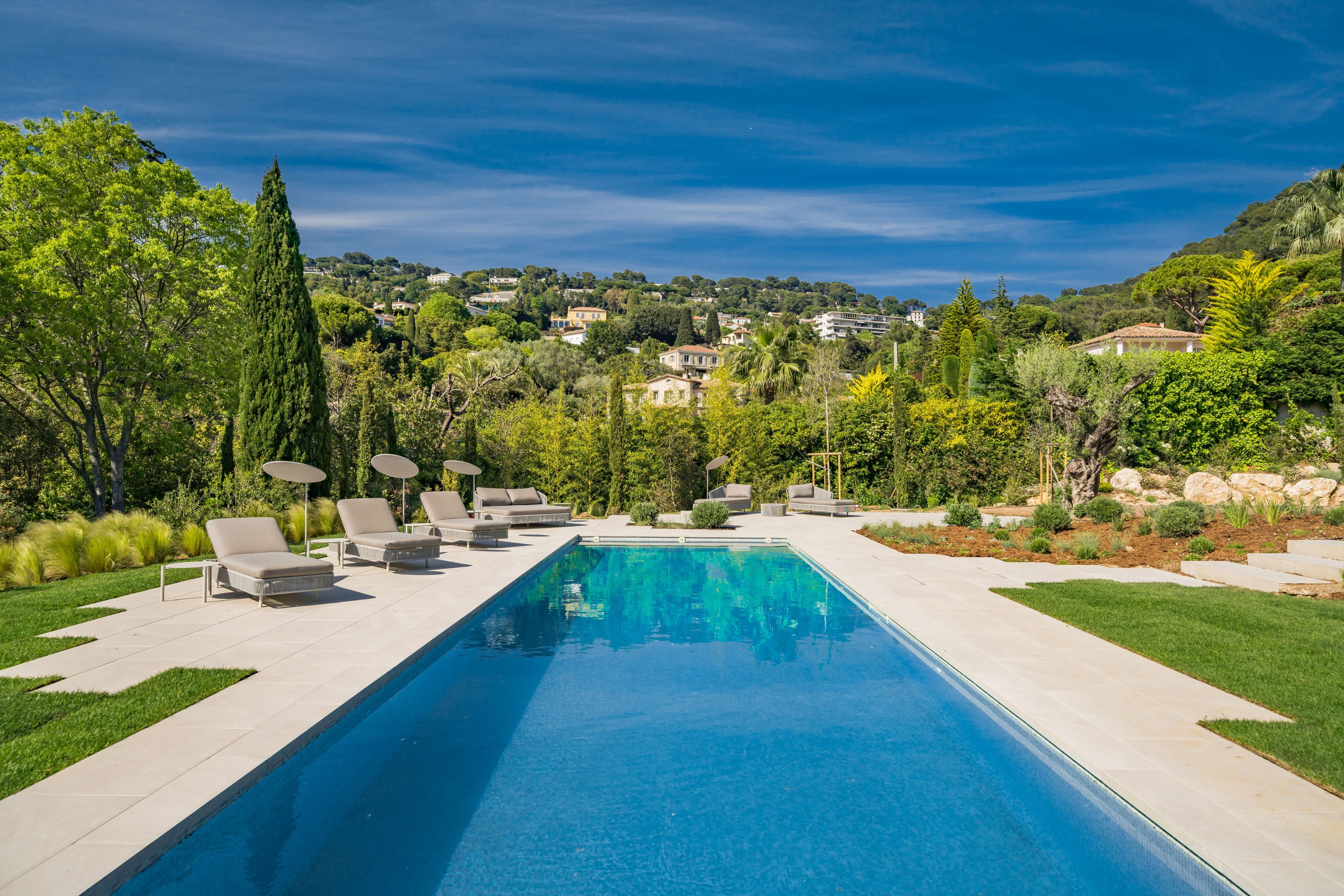 Long heated pool at Villa Fanny surrounded by lush greenery, loungers, and minimalist landscaping for luxury outdoor living