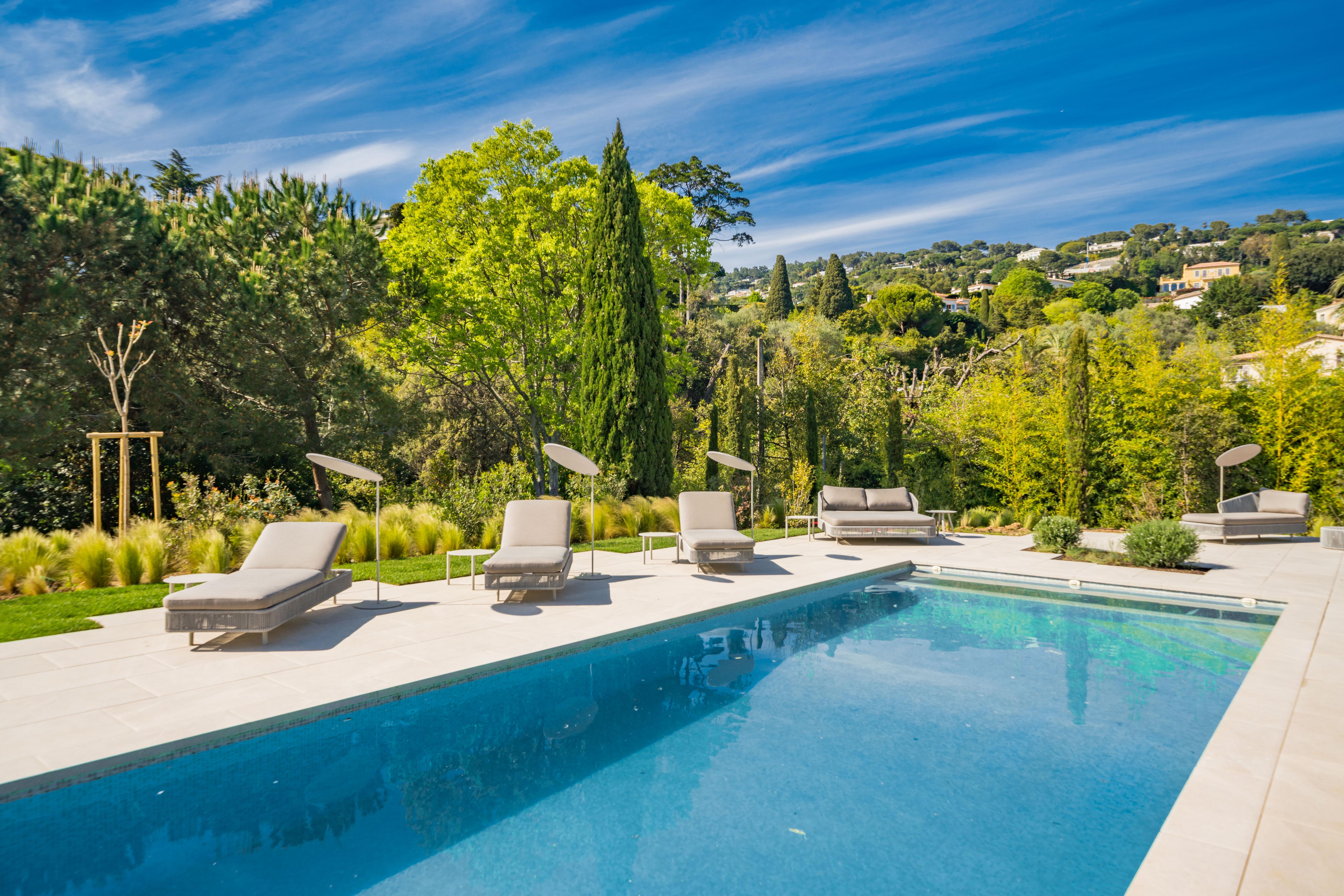 Tranquil poolside terrace at Villa Fanny with sun loungers, shaded seating, and landscaped gardens set against the Cannes hills