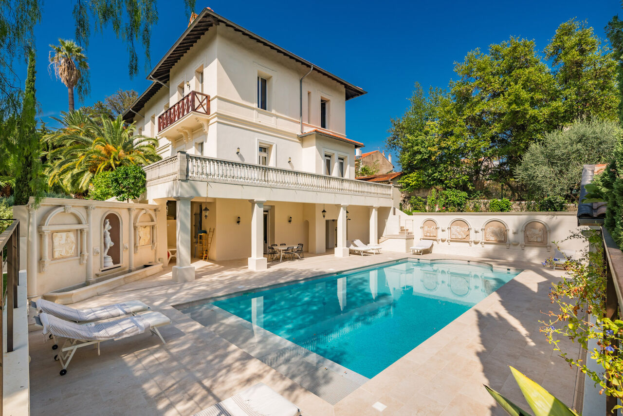 Elegant poolside view of Villa Iris, highlighting Belle Époque façade, mature greenery, and serene Provençal outdoor living space