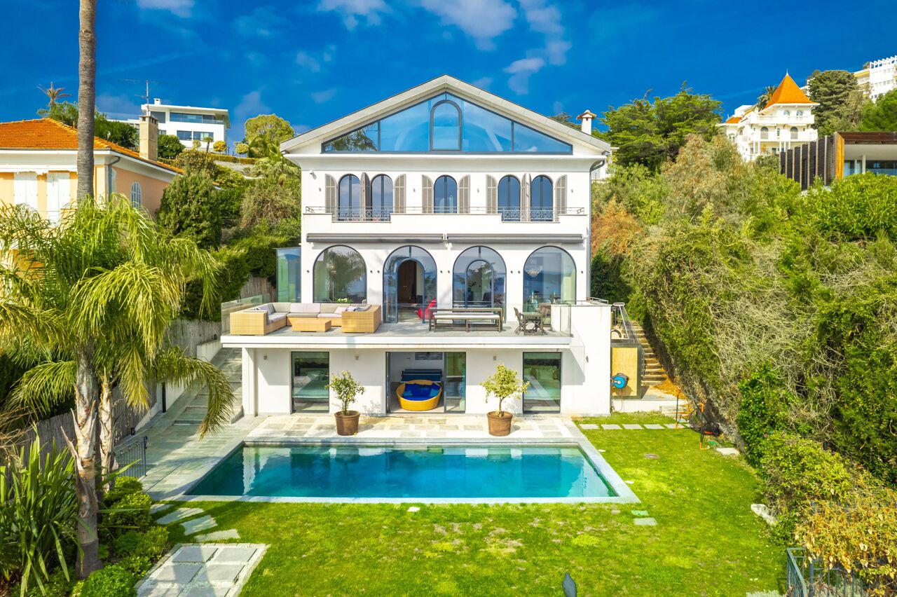Symmetrical façade of Villa Nirvana with arched windows, lush garden, and central pool offering a peaceful escape in the heart of the French Riviera