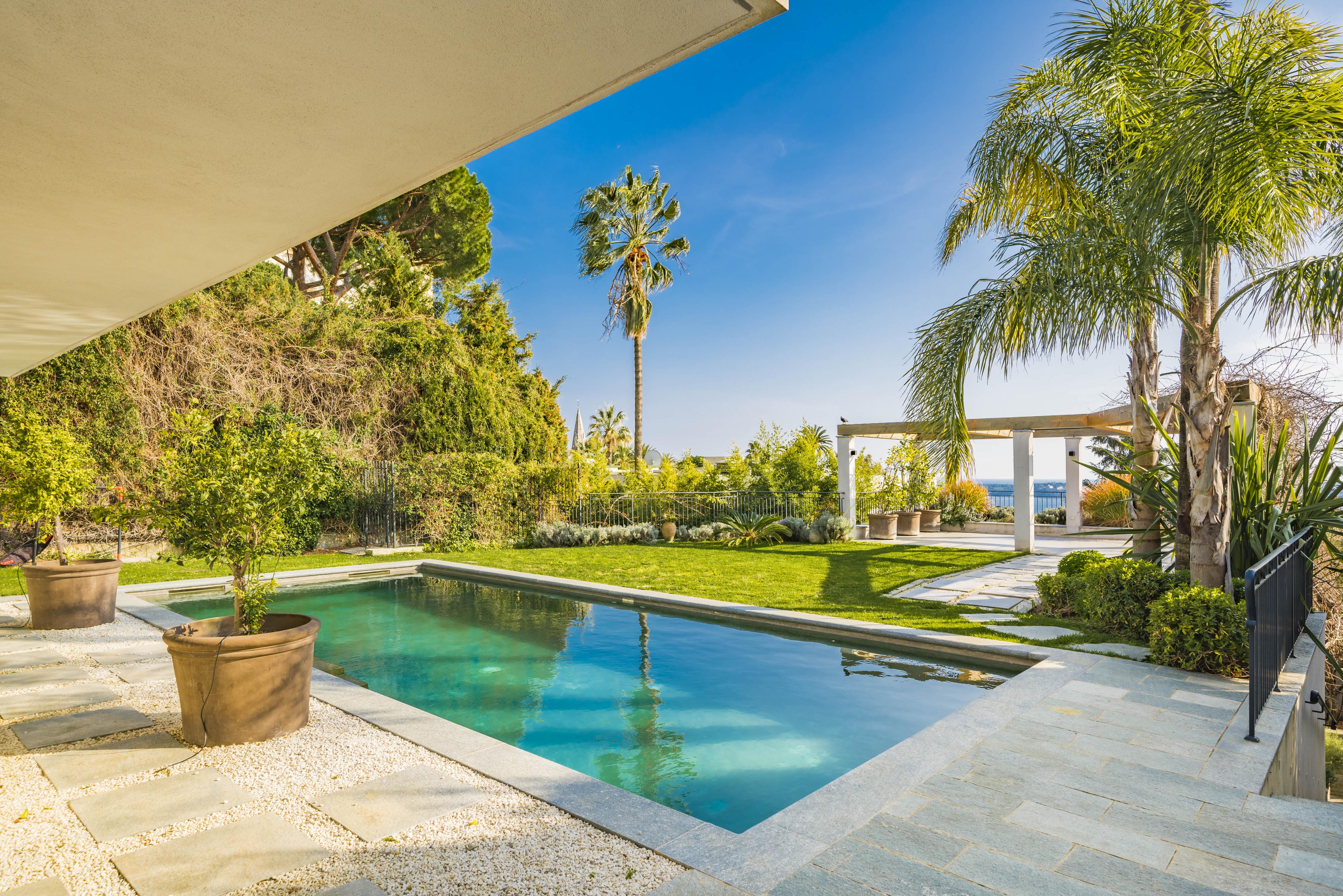 Tranquil poolside terrace at Villa Nirvana with sea views, tropical landscaping, and shaded lounge areas perfect for outdoor relaxation in Cannes