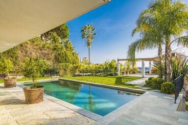 Tranquil poolside terrace at Villa Nirvana with sea views, tropical landscaping, and shaded lounge areas perfect for outdoor relaxation in Cannes