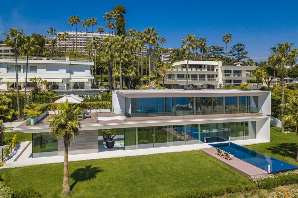 Contemporary Villa Ophelia in Cannes with floor-to-ceiling windows, manicured gardens, and a sleek private pool overlooking the Mediterranean