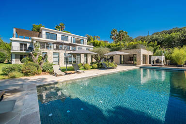 Poolside view of Villa Phoenix showing modern architecture, sun loungers, and landscaped gardens designed for luxury outdoor living