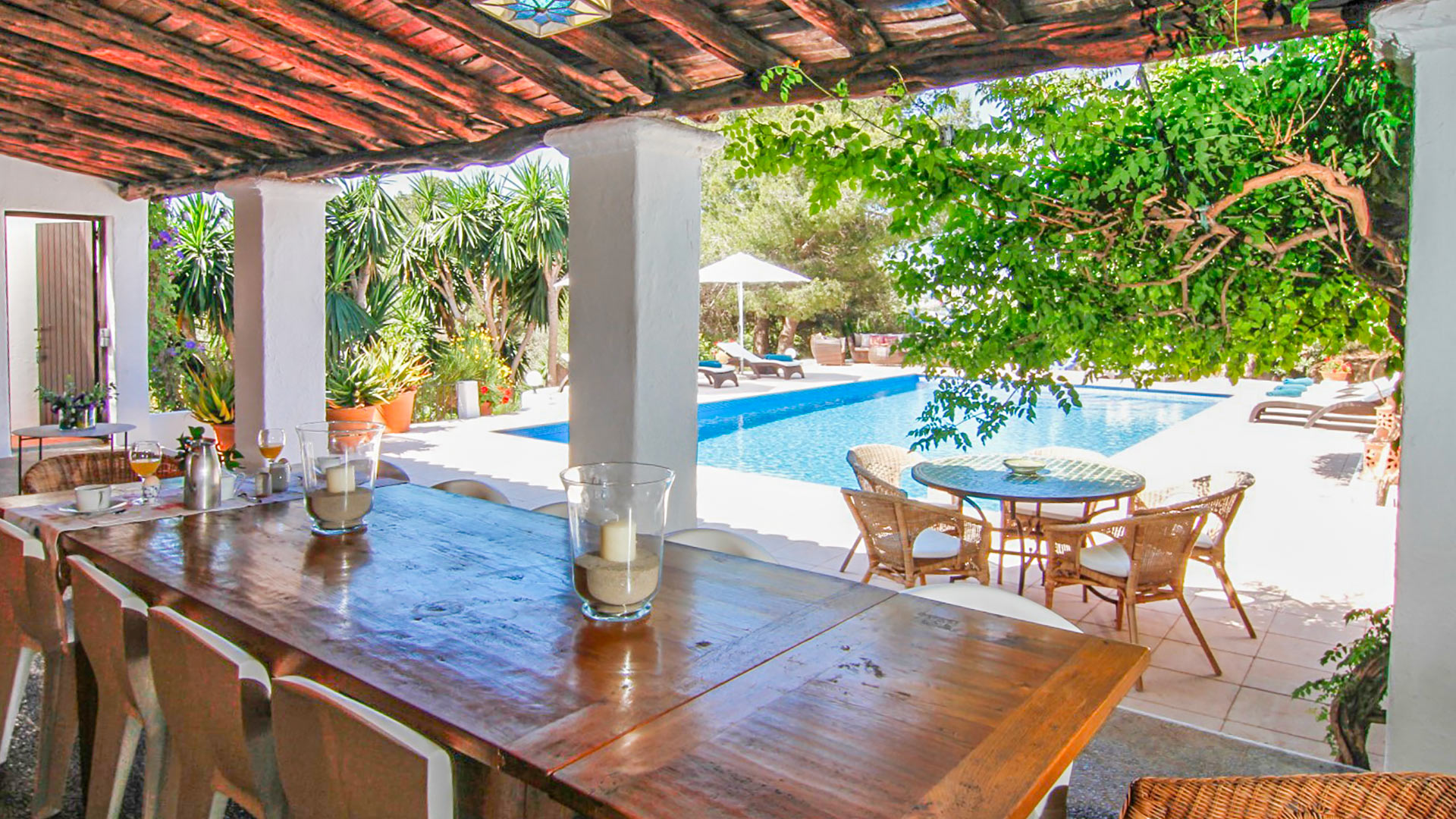 Shaded poolside pergola in Can Bab in Ibiza with large dining table for alfresco dining