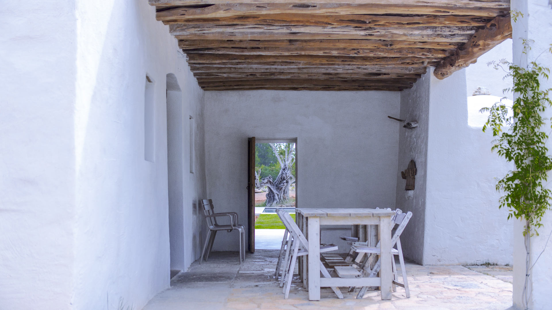 White stained wooden dining table under wooden pergola at Villa Can Basso rental from Bluemoon