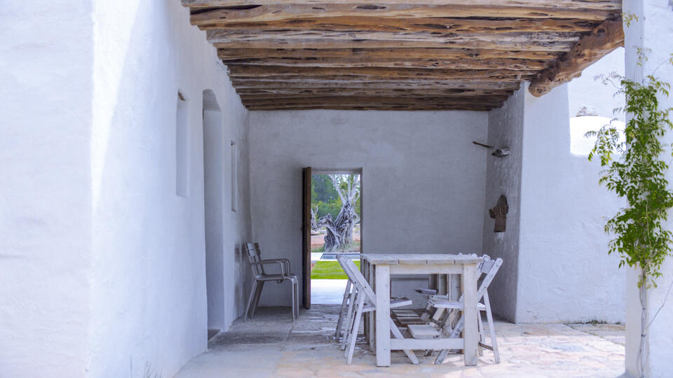 White stained wooden dining table under wooden pergola at Villa Can Basso rental from Bluemoon