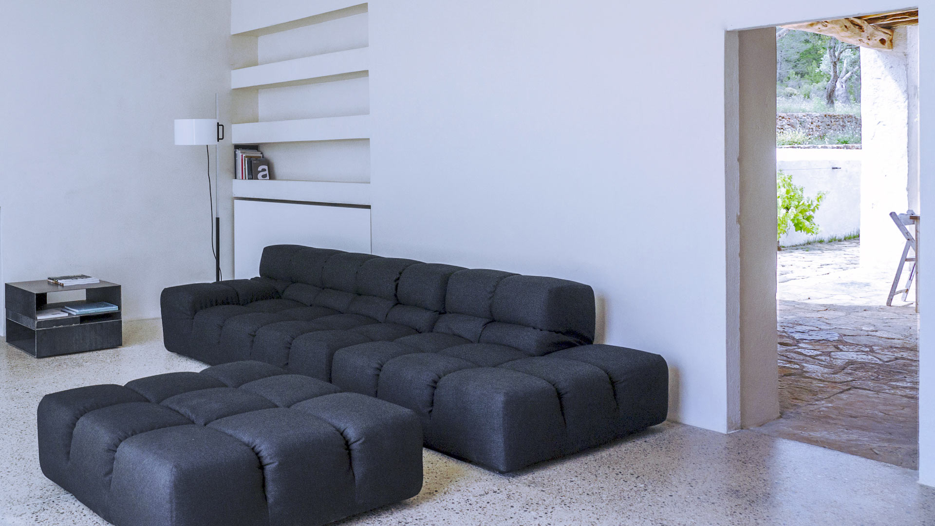The modern sofa in the living space leading out to the exterior dining area at Villa Can Basso in Ibiza