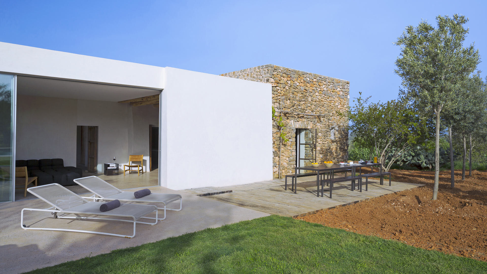 Exterior of the luxury rental with sunbeds and dining table at Villa Can Basso in Ibiza