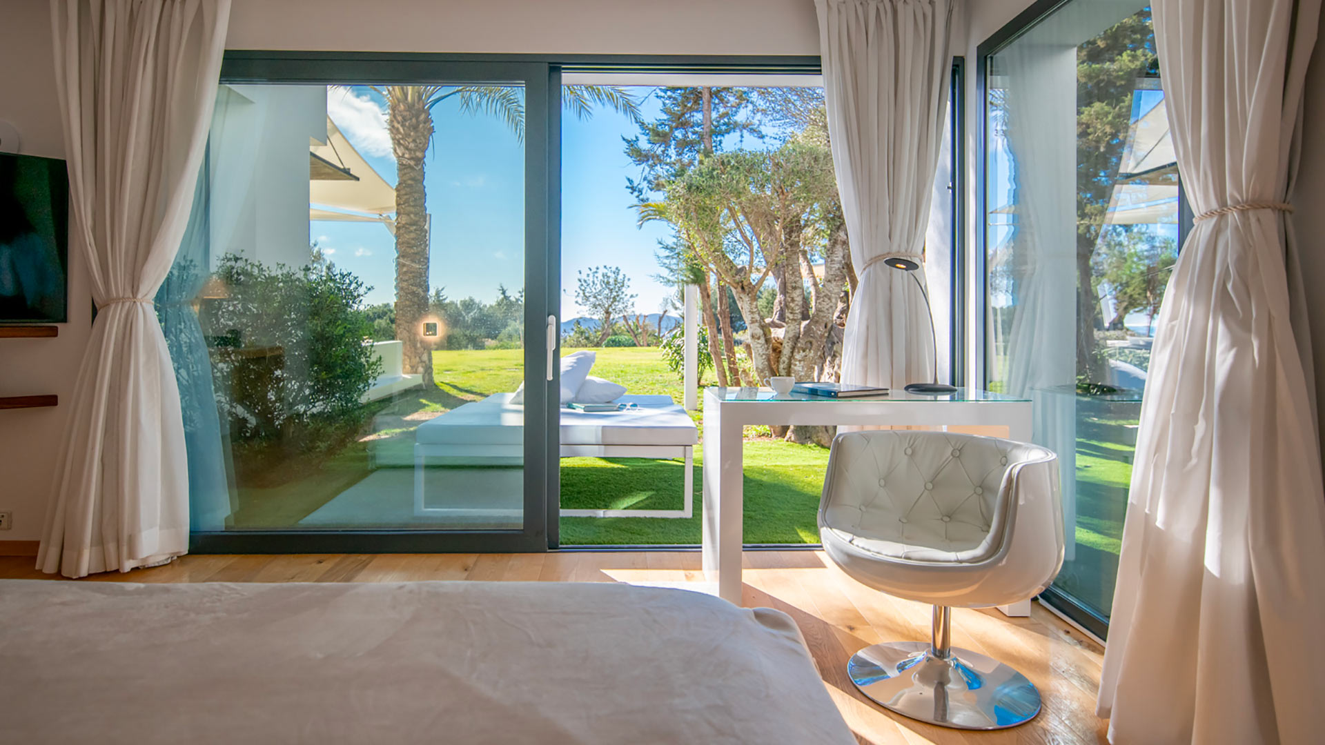 Floor to ceiling windows in one of the bedrooms with a chair at Villa Casa Isa in Ibiza