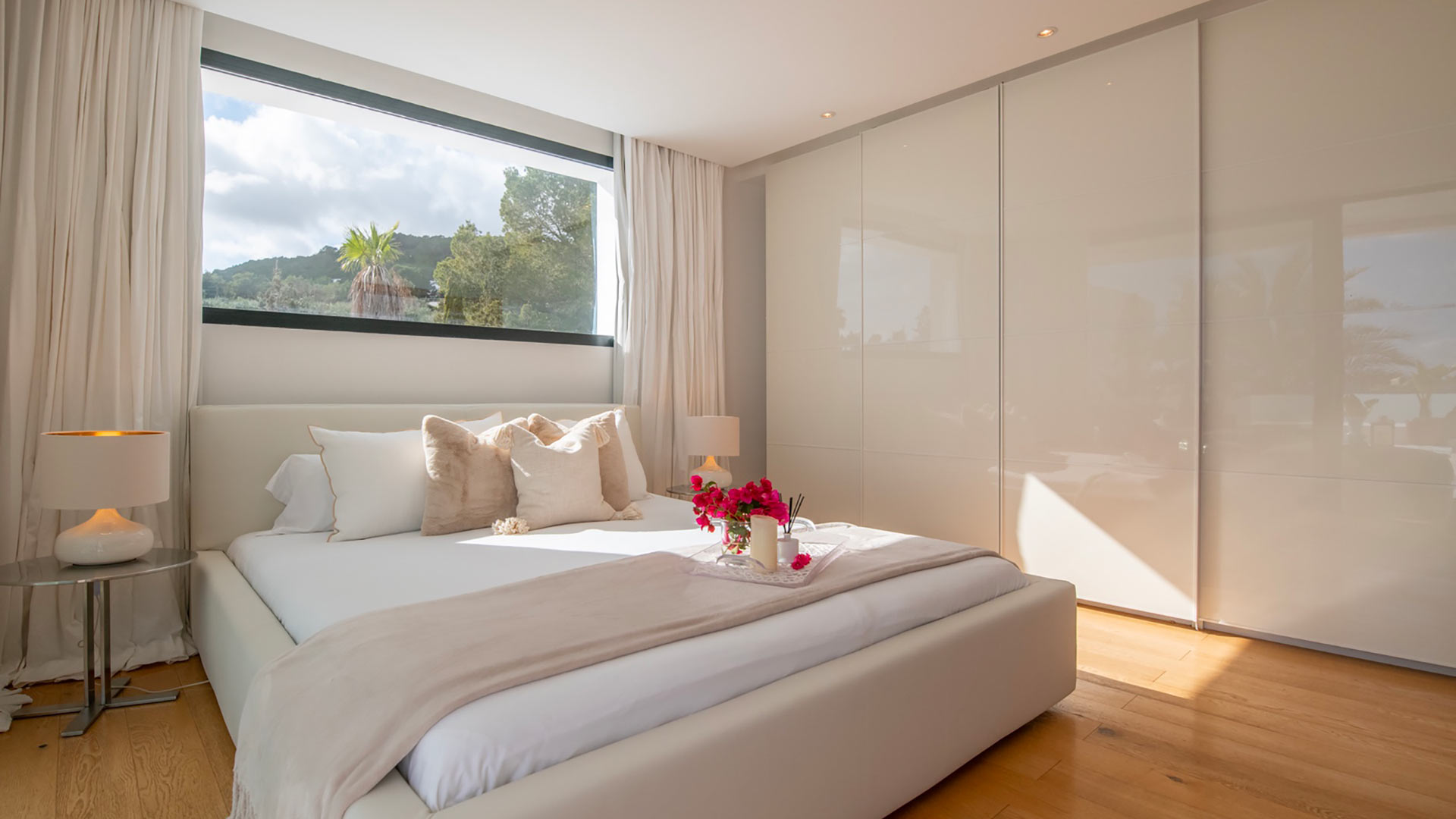 Bedroom with a giant window above the bed and built in wardrobes at Villa Casa Isa in Ibiza