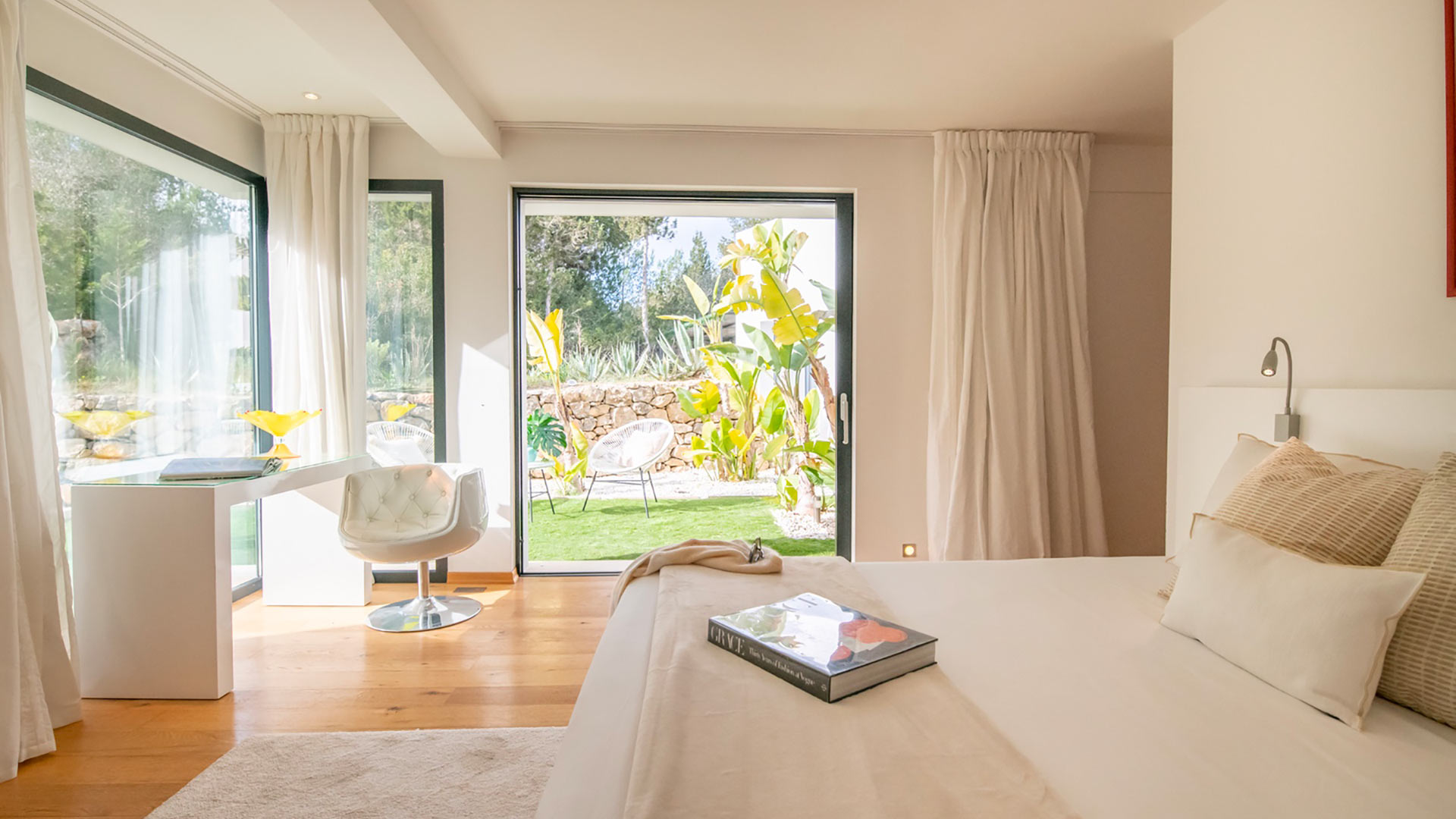 One of the large bedrooms at Villa Casa Isa in Ibiza with soft neutral furnishings and patio doors directly into the garden