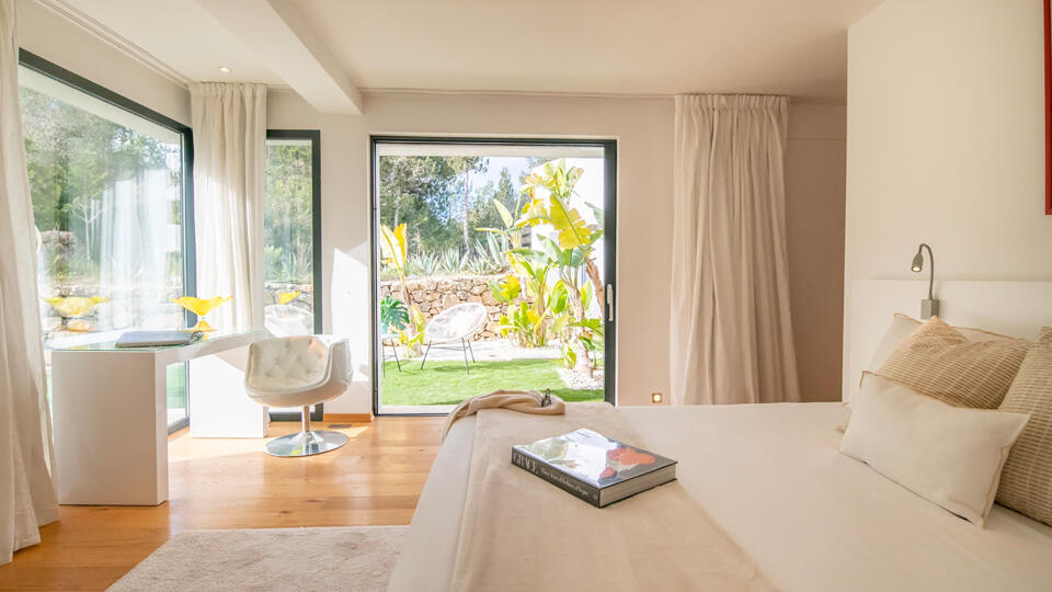 One of the large bedrooms at Villa Casa Isa in Ibiza with soft neutral furnishings and patio doors directly into the garden