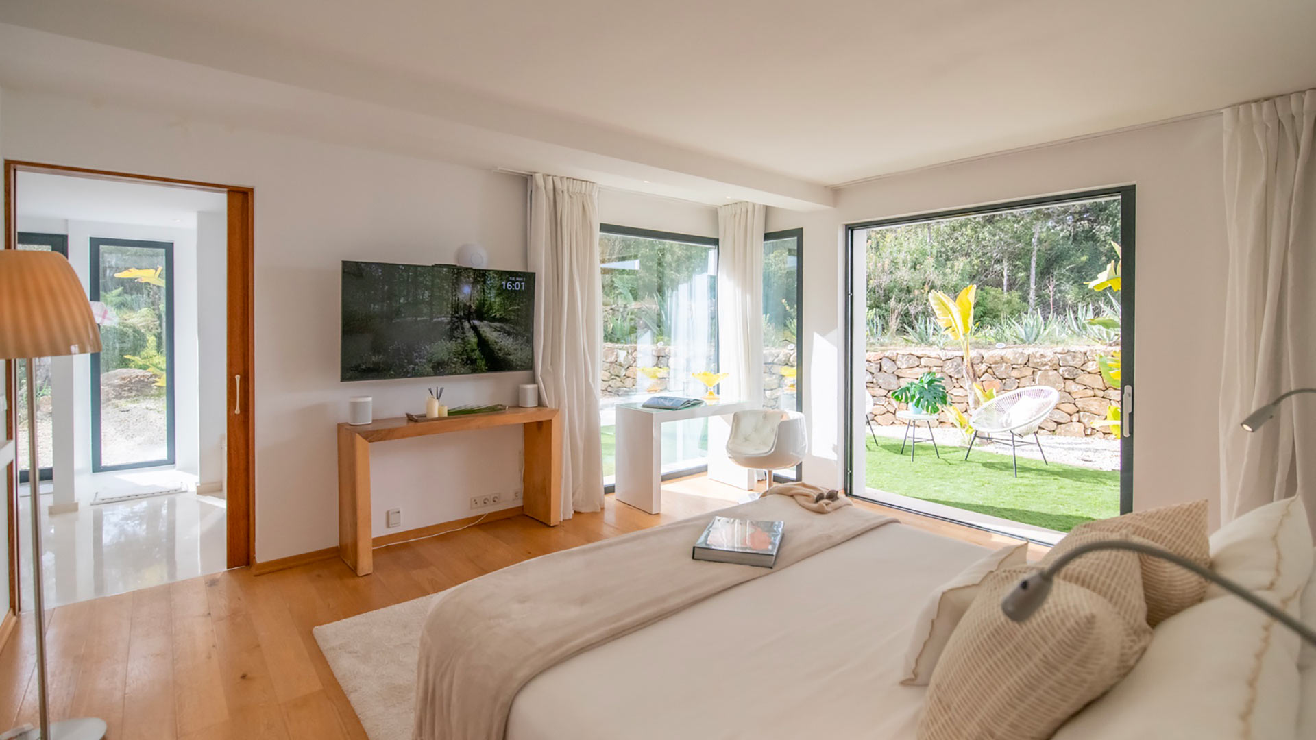 A large bedroom in Villa Casa Isa in Ibiza with a big TV opposite the bed and big patio doors into the garden