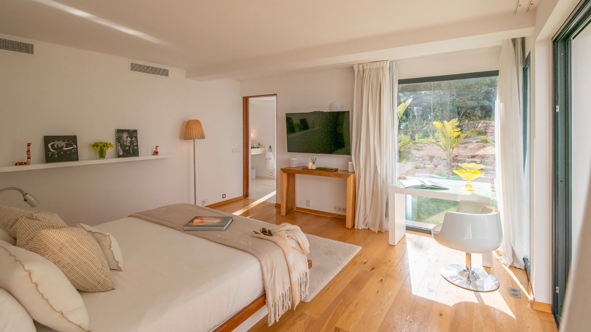 One of the large bedrooms in Villa Casa Isa in Ibiza with big large windows with beautiful sunlight streaming in