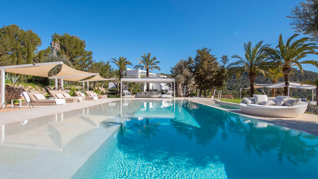 Swimming pool glistening under the Ibiza sun with plenty of sunbeds and loungers surrounding it at Villa Casa Isa