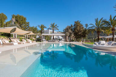 Swimming pool glistening under the Ibiza sun with plenty of sunbeds and loungers surrounding it at Villa Casa Isa