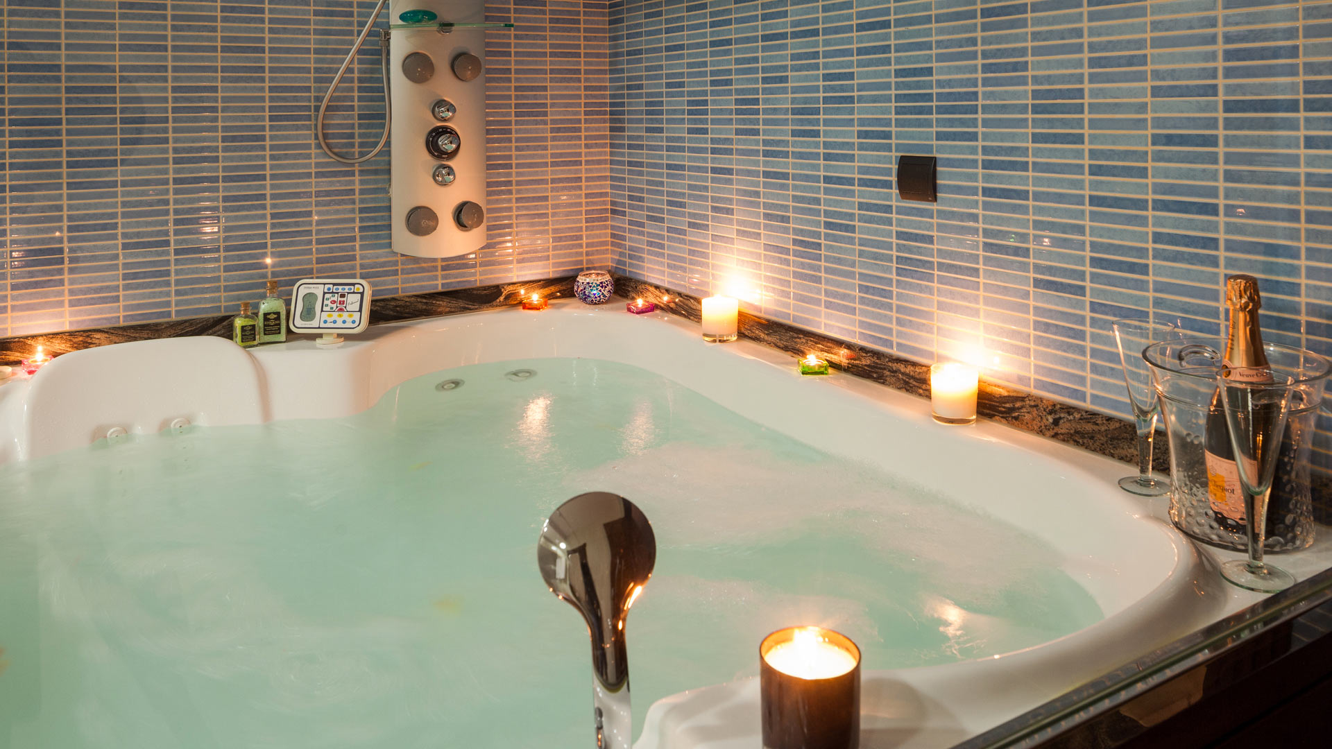 Large jacuzzi style bathtub lit up in the dark bathroom at Villa Fountain Ibiza