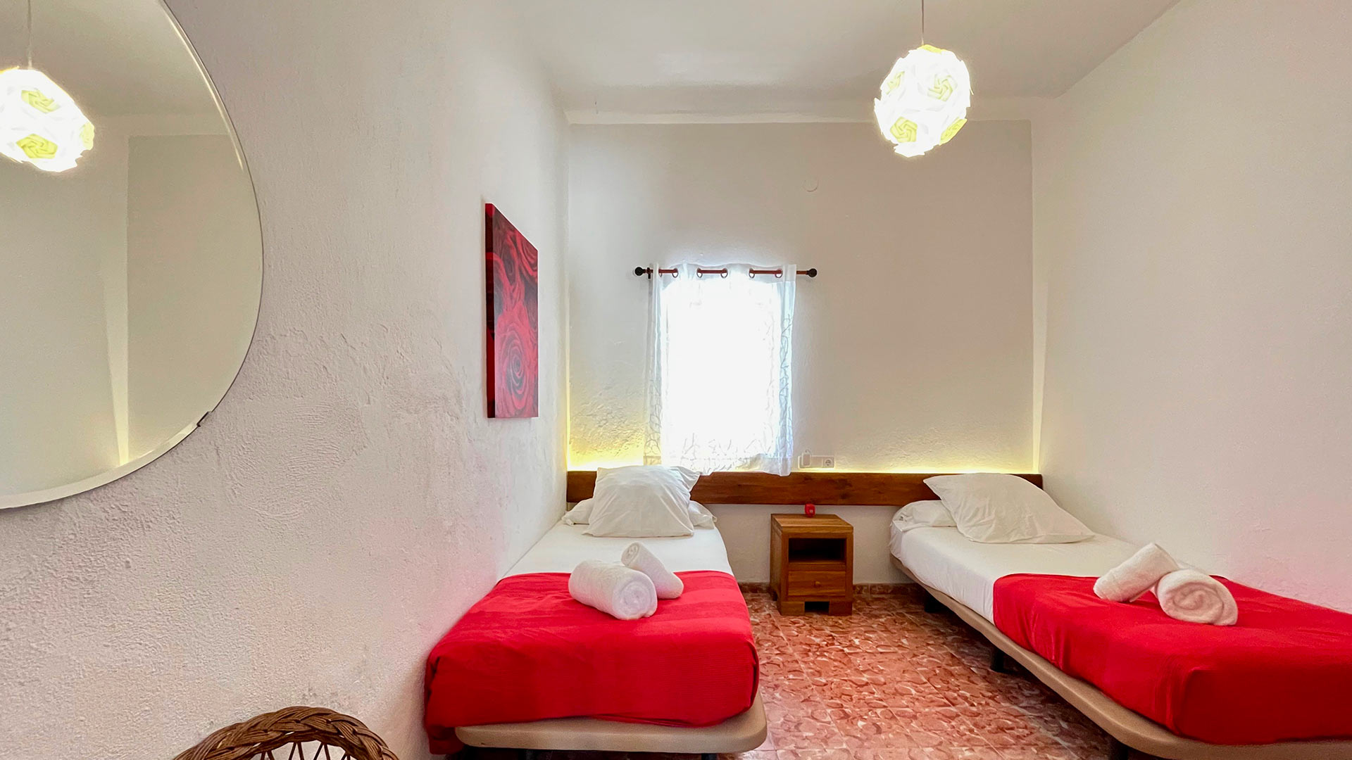 Twin bedroom with red and white linens in Villa Torre Pau in Ibiza