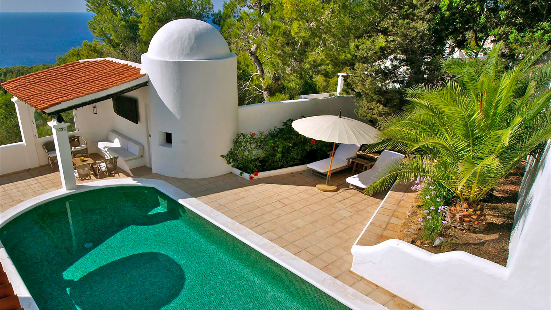 View from one of the higher parts of Villa Trillo in Ibiza and the green hued swimming pool