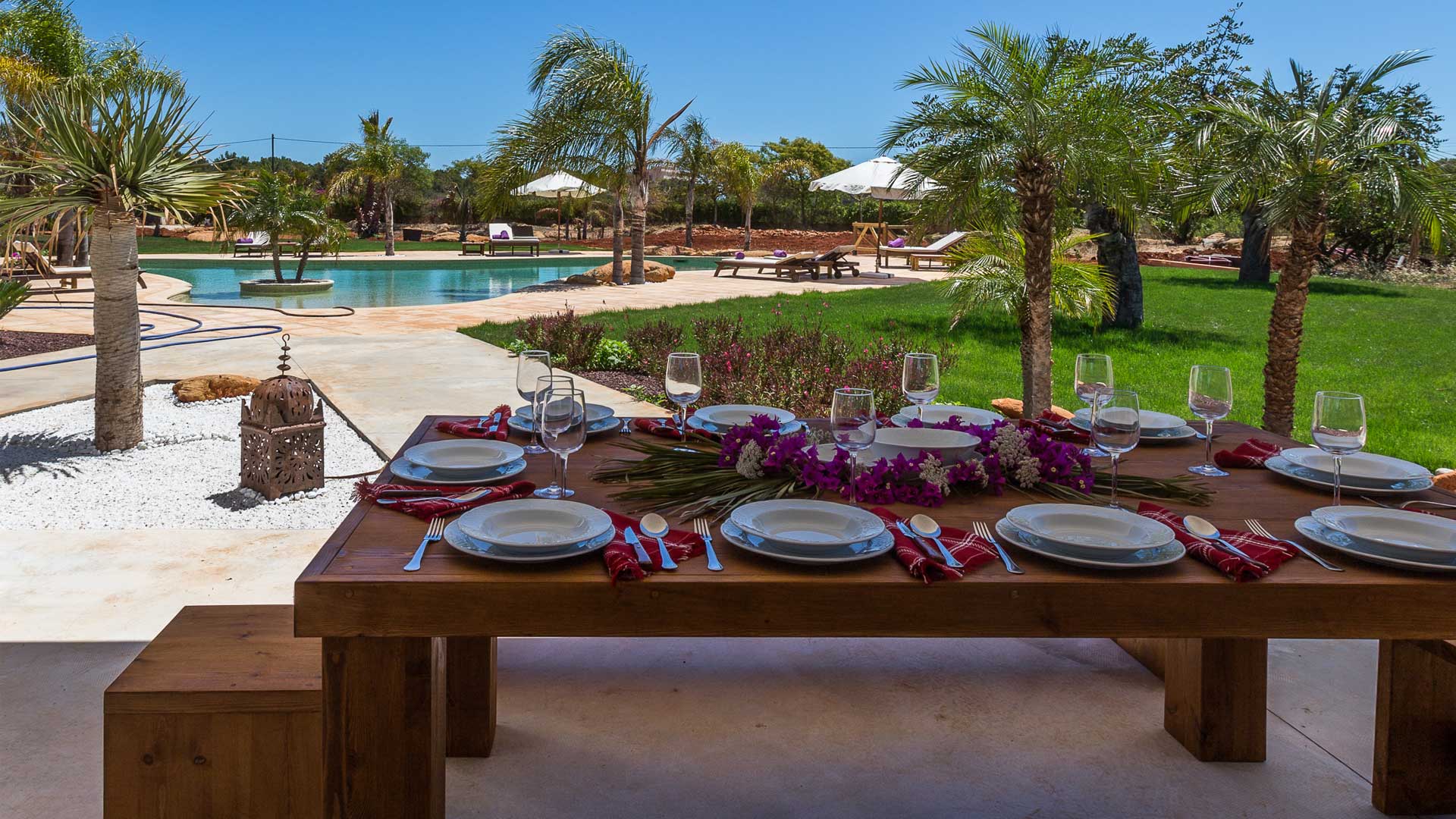 Shaded dining area with a bench and pool at Villa Es Canar in Ibiza