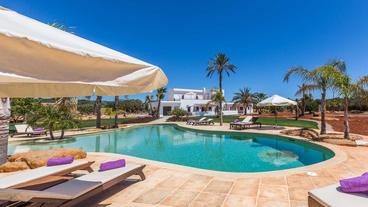 Sunbeds around the lagoon style pool at Villa Es Canar in Ibiza