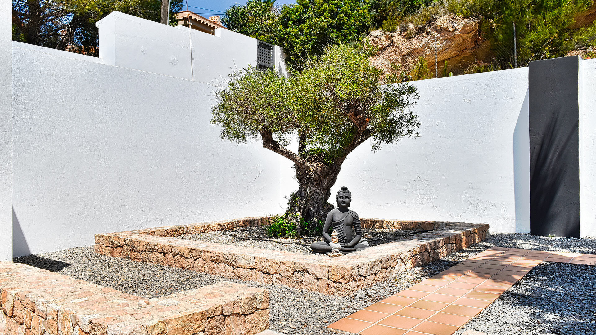 A zen exterior area with beautiful tree and Buddha statue at Villa White Beach in Ibiza