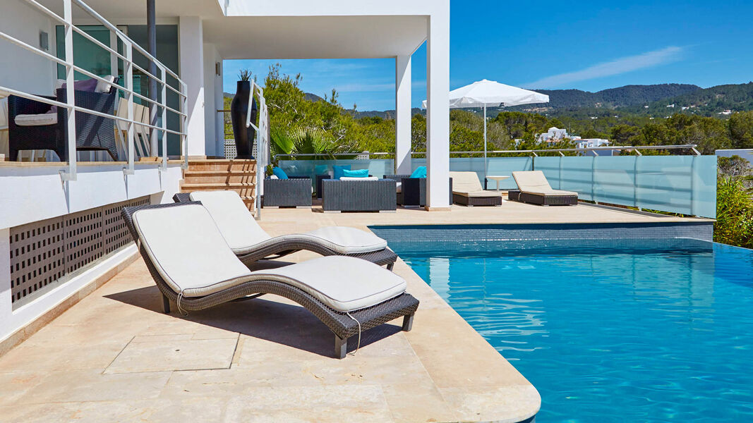 Sunloungers poolside at Villa White Beach in Ibiza with deep blue water