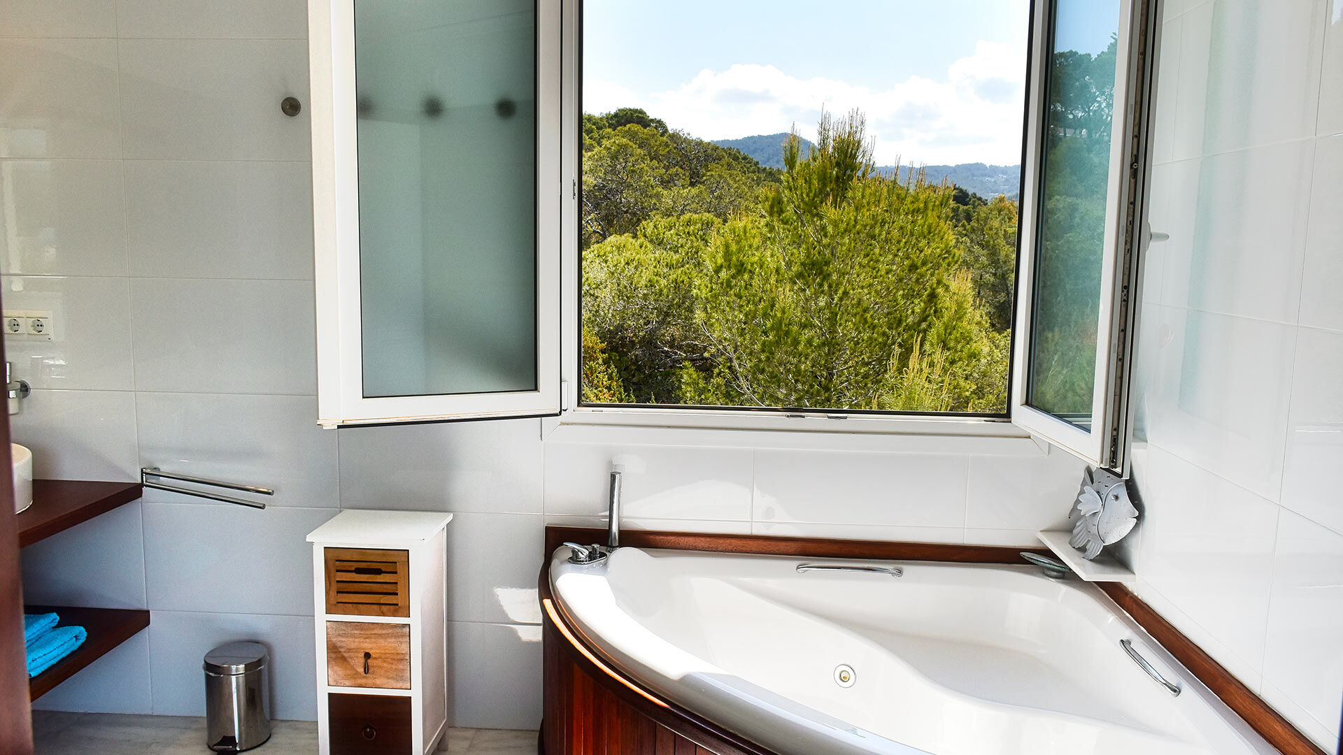Open window from one of the bathrooms in Ibiza with a treefilled view at Villa White Beach in Ibiza