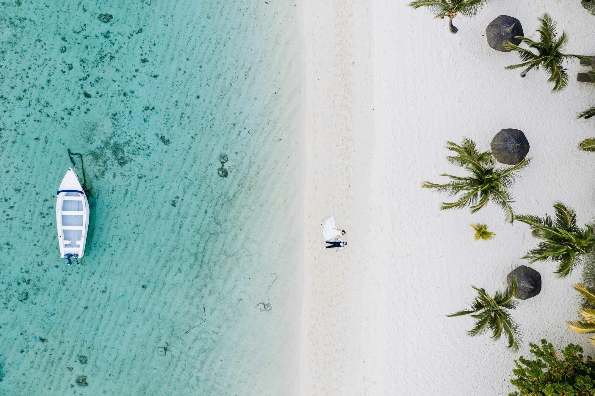 Aerial shot of Mauritius Beach and the white sands and clear blue waters with a recently married couple