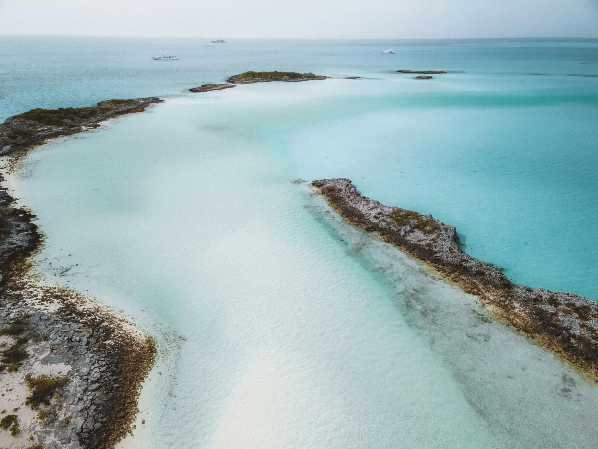 The sea in the Bahamas with two yachts at anchor in the distance