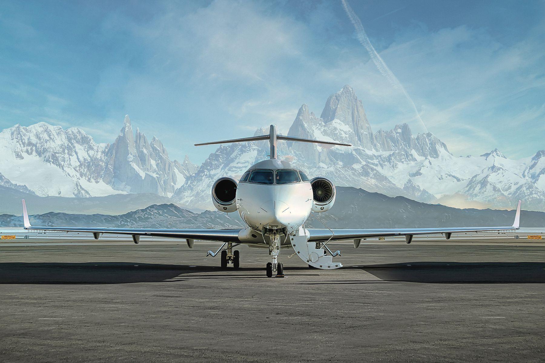 A private jet with the stairs down ready for boarding in front of mountains