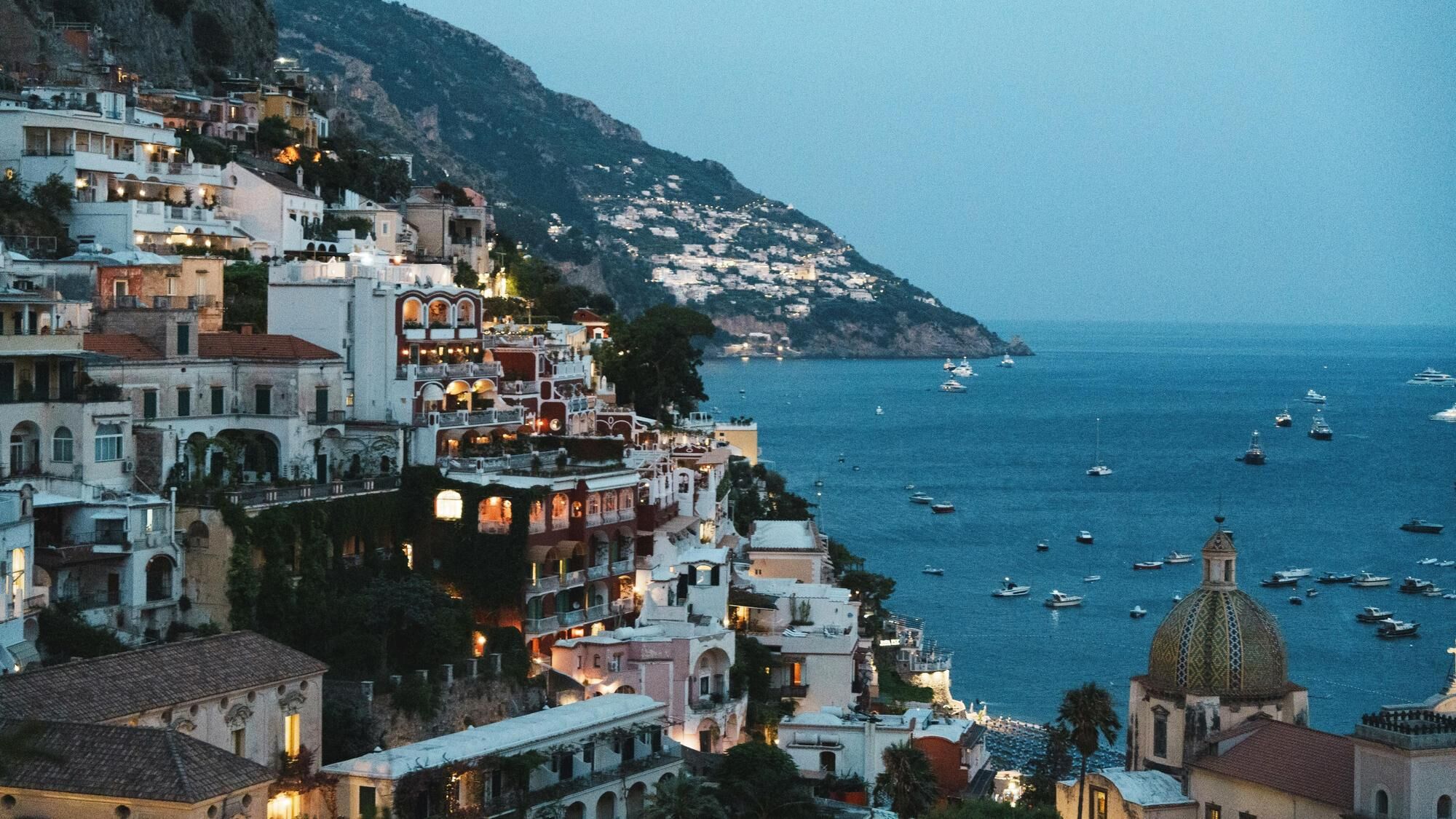 Homes in Positano in the evening with yachts in the sea