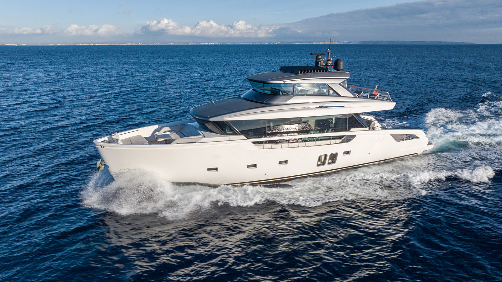 Port view of charter yacht Cloud IX sailing through the sea leaving waves behind it