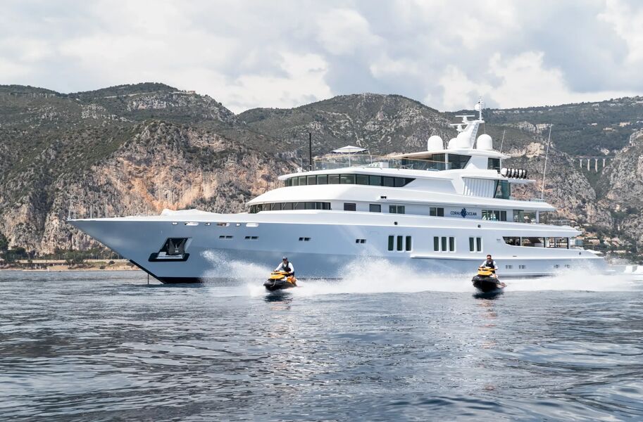 Two people on jet skis in front of super yacht Coral Ocean on charter