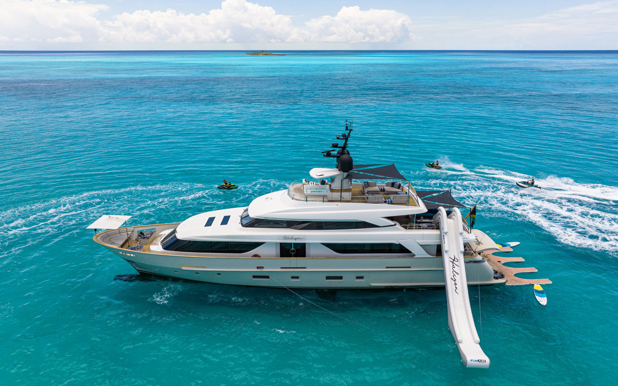 Motor yacht Halcyon at anchor with inflatable slide out and charter guests jet skiing around