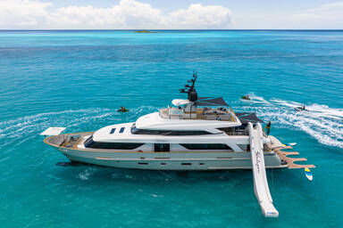 Motor yacht Halcyon at anchor with inflatable slide out and charter guests jet skiing around